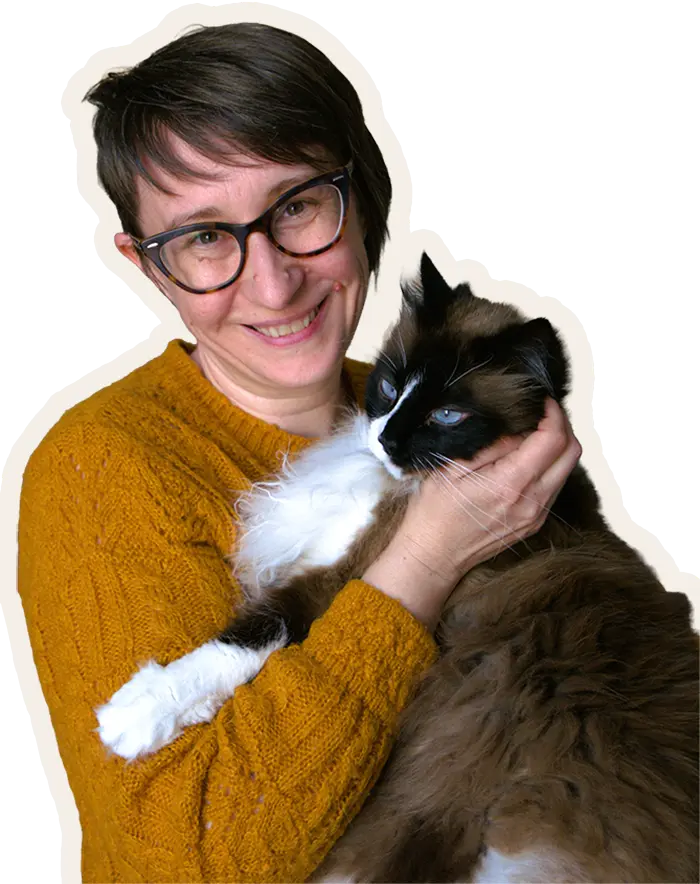 Morgane, souriante, tenant dans ses bras un chat typé Sacré de Birmanie aux yeux bleus.